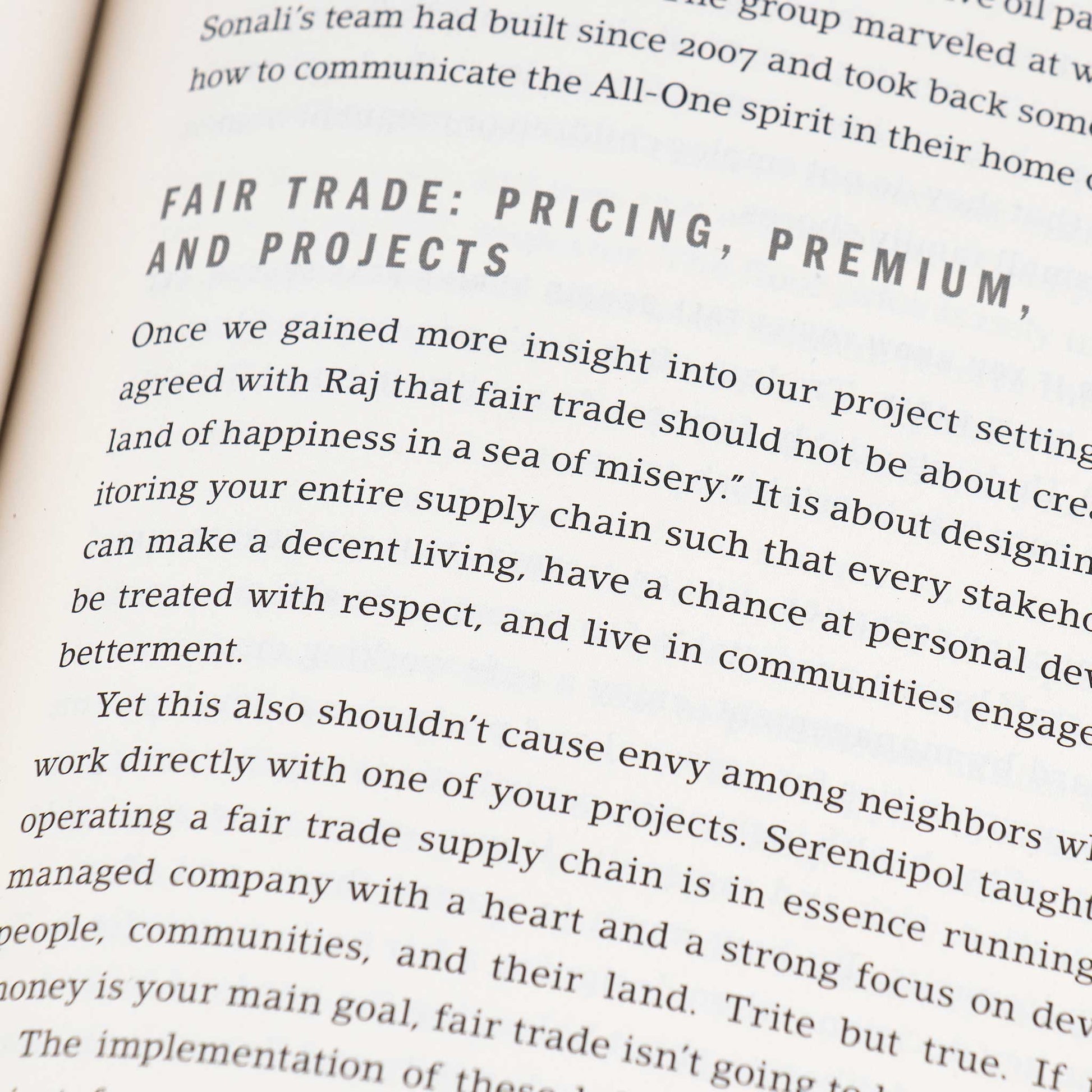 A close up of a book page, focusing on a chapter titled Fair Trade Pricing, Premium, and Projects. The text discusses fair trade concepts, emphasizing equitable supply chain practices for community betterment